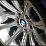 Close-up of a silver alloy wheel with the BMW logo in the center. The multi-spoke wheel is attached to a dark-colored vehicle, showcasing top-notch car valeting services with paint protection film for added durability.