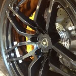 Detailed close-up of a black alloy wheel with a yellow brake caliper and drilled brake rotor, enhanced by a smooth ceramic coating.