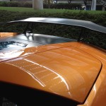 Close-up of an orange sports car's rear, focusing on its spoiler and sleek design features, highlighting expert car detailing.