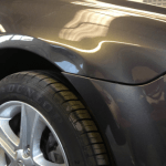 A close-up view of a car's front fender and wheel, showcasing a noticeable dent on the fender above the tire—ideal for highlighting the benefits of ppf.