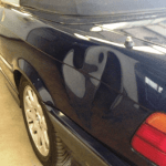 A dark blue car with a distorted reflection of a bird or duck shape on the rear quarter panel can benefit from ppf to maintain its pristine look.