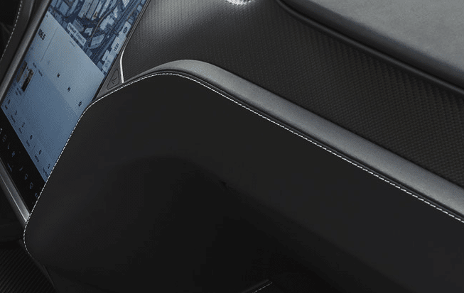 Close-up view of a sleek car dashboard featuring a digital display screen and black leather trim with white stitching, enhanced by ceramic coating.