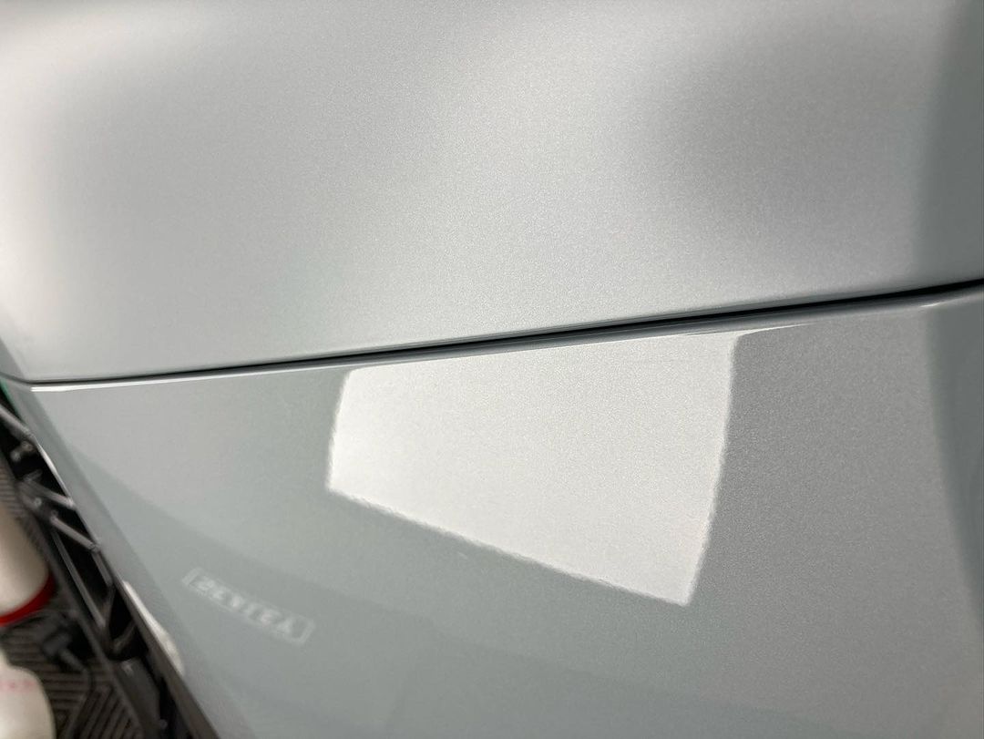 Close-up view of a silver, metallic car door with a subtle reflection and slight gap between the door and the main body, showcasing the sleek finish provided by a ceramic coating.